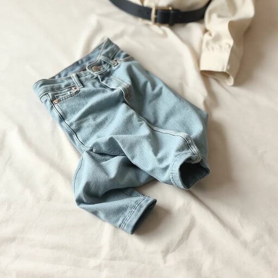 Leichte Stretch-Jeans mit sauberer Passform auf hellem Hintergrund, natürliche Stofffalten und weiches Tageslicht
