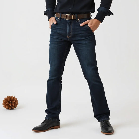 Person in dunkelblauen Slim-Fit-Jeans mit betonter Passform und sichtbarer Stoffstruktur vor neutralem Hintergrund