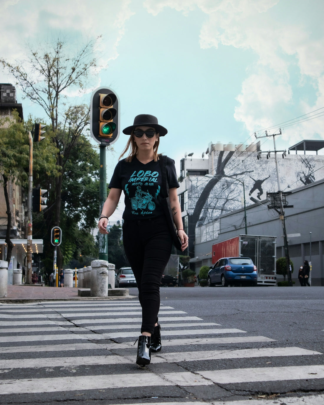 man in green t-shirt and black pants wearing black hat standing on road during daytime