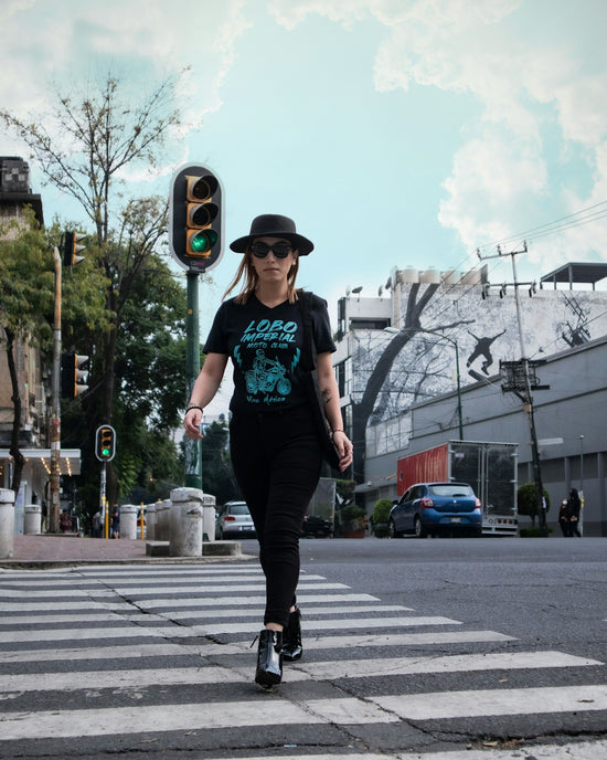 man in green t-shirt and black pants wearing black hat standing on road during daytime