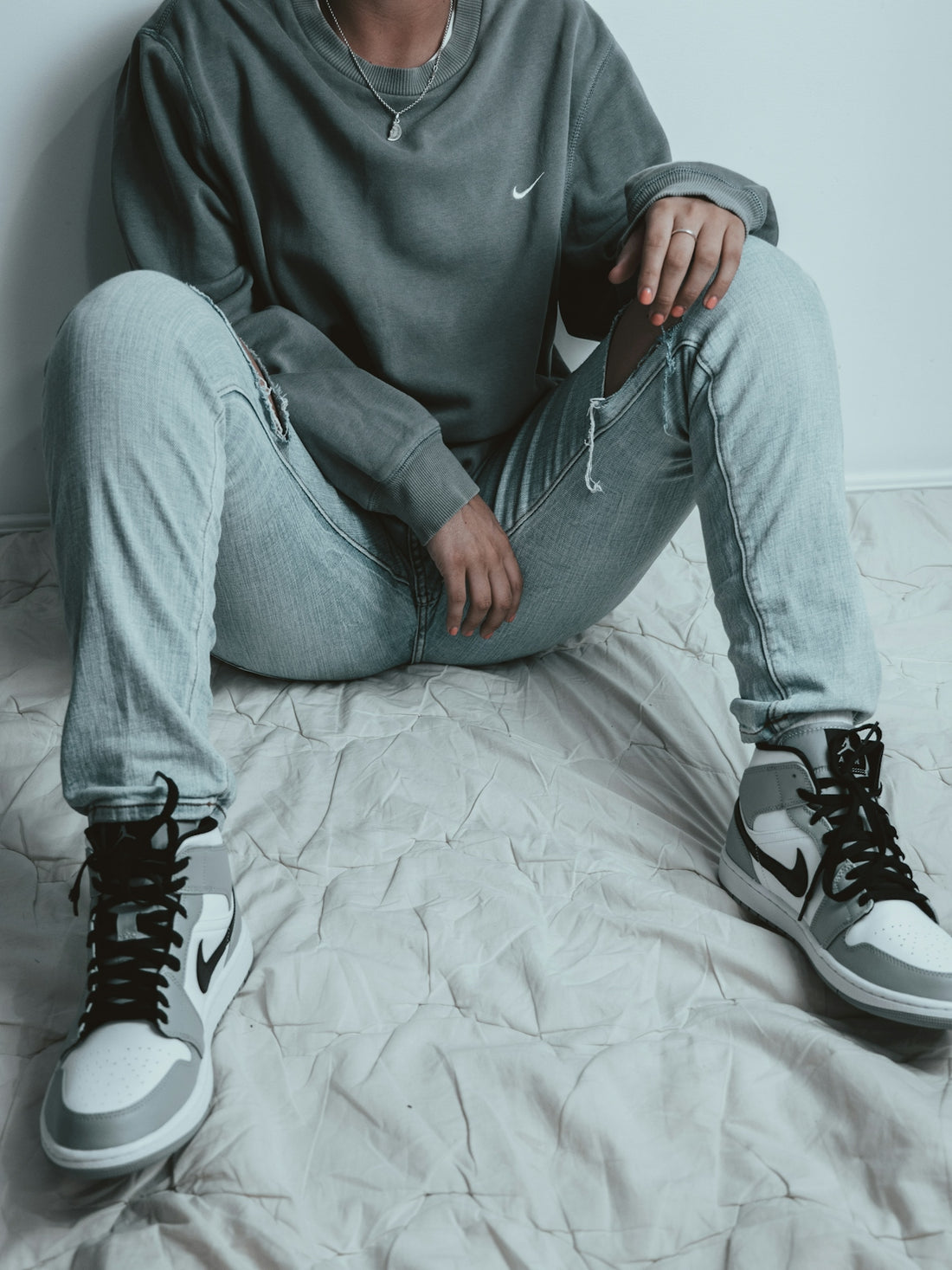man in gray sweater and gray denim jeans sitting on bed