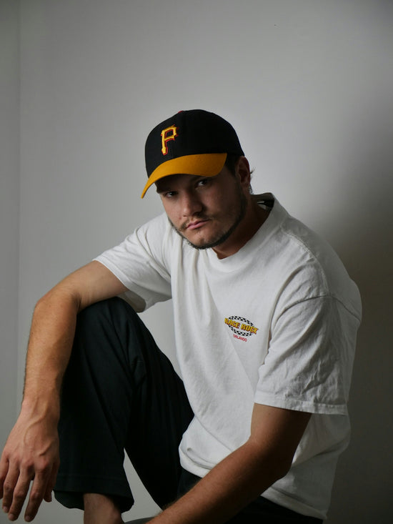 man in white crew neck t-shirt and orange and black cap sitting on chair
