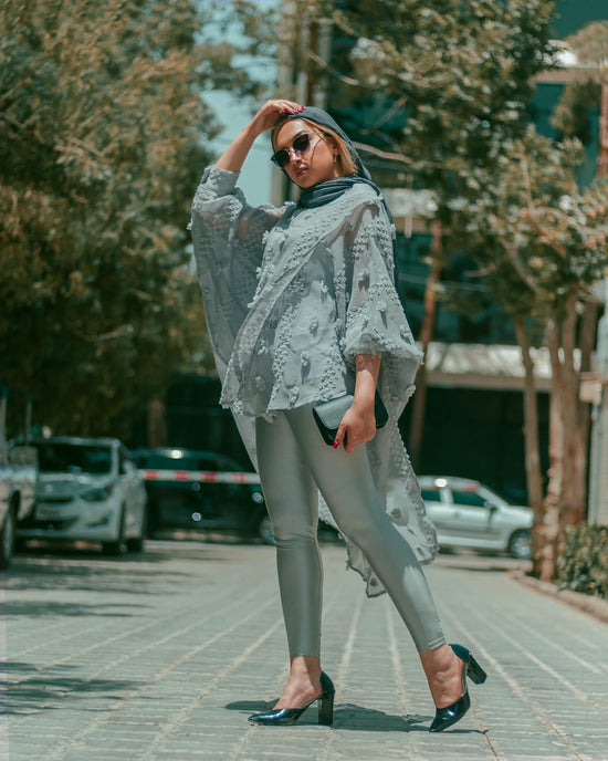 a person wearing a white dress and sunglasses walking on a sidewalk