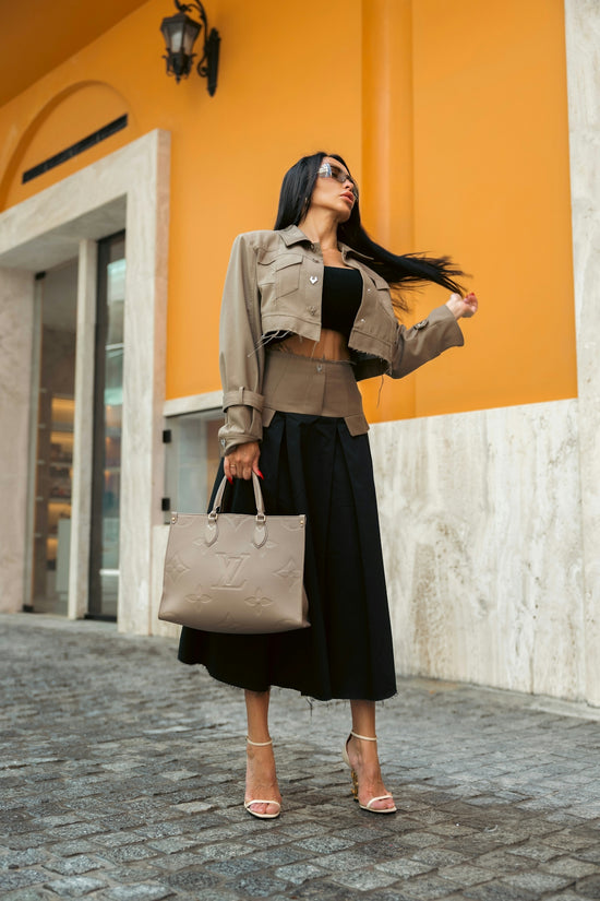 A stylish woman poses outdoors with a designer handbag.