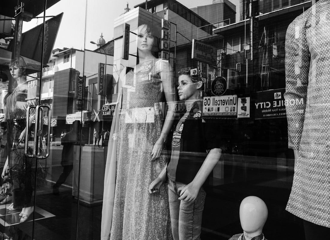 Child stands beside mannequin in store window display