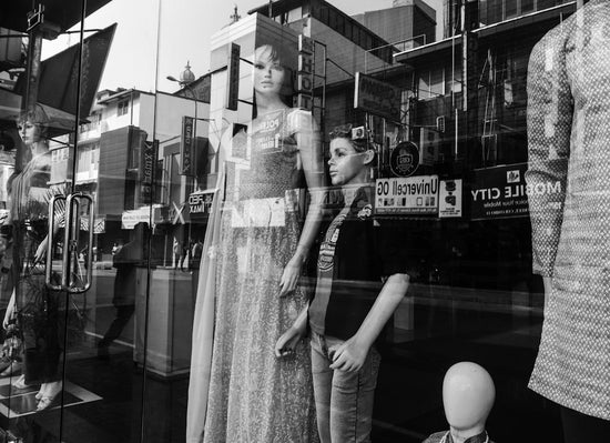 Child stands beside mannequin in store window display