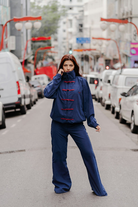 Woman in blue chinese-style outfit on a city street.