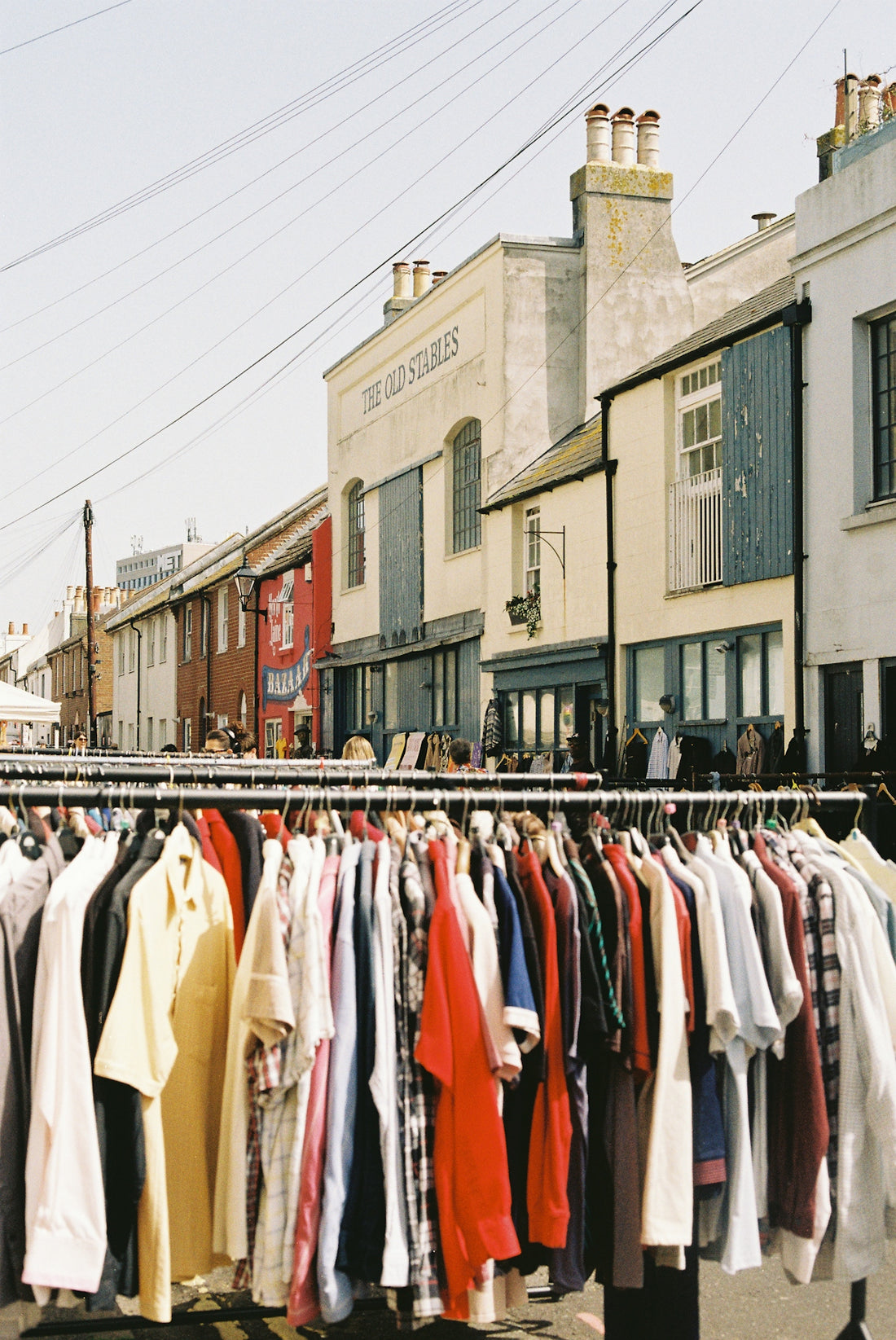 Clothing rack with buildings on a sunny street.