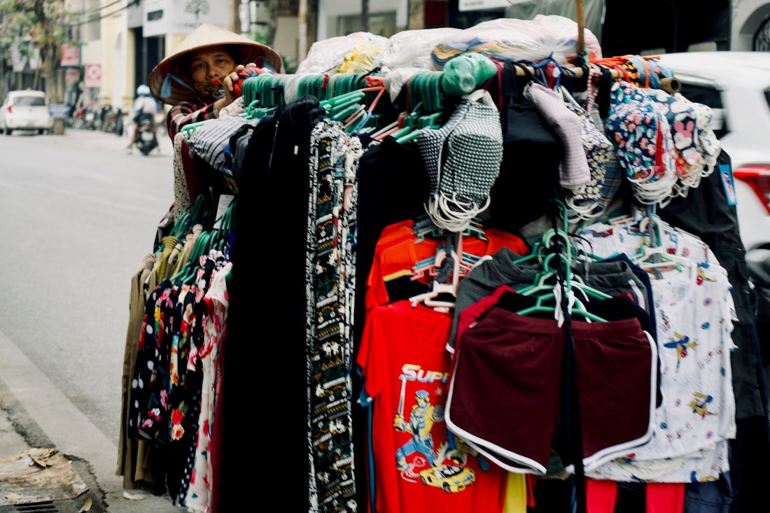 Person in conical hat selling clothes from a street stall