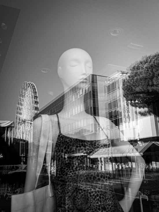 A double exposure of a mannequin in a leopard print dress and a ferris wheel.